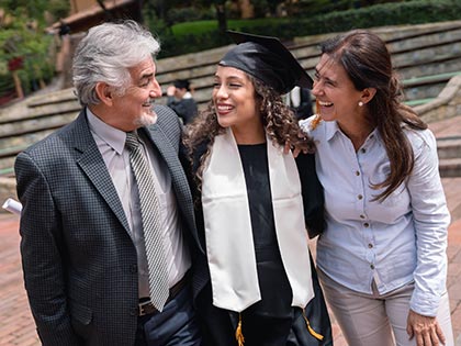 A mum and dad hugging their daughter celebrating her college graduation