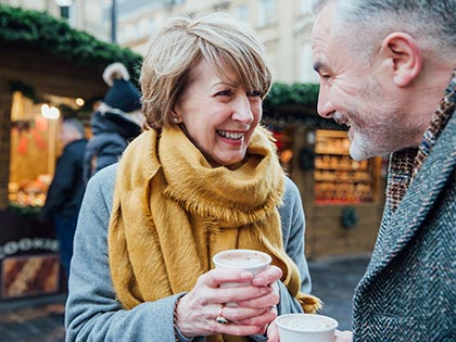 Mature man and woman enjoying a coffee together at an outdoor market